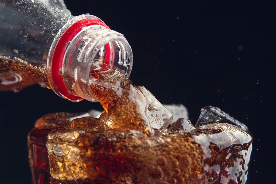 Refresco de cola sirviéndose en un vaso con hielo